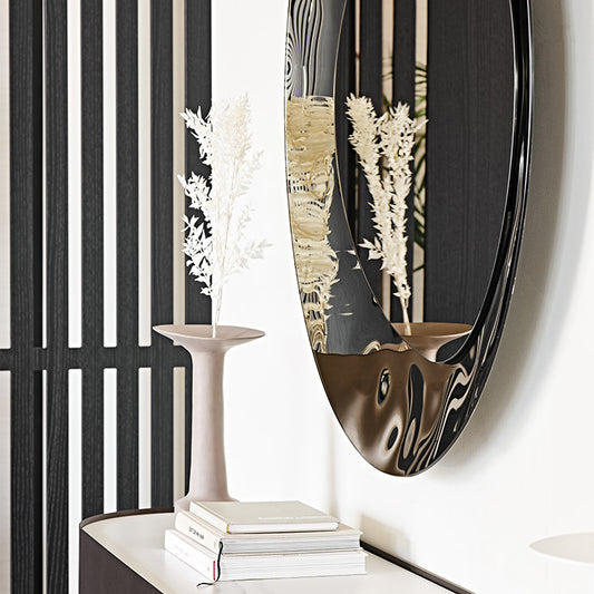 A close up image of the side profile of the bronze mirror hung on a white wall.