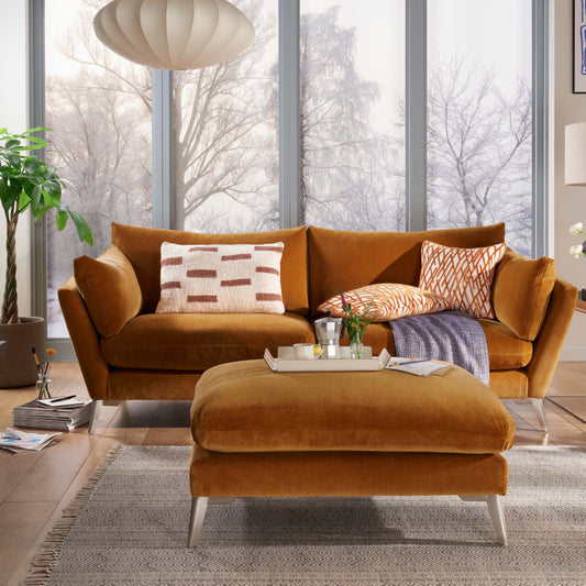Modern living room with brown sofa, ottoman, and fireplace.