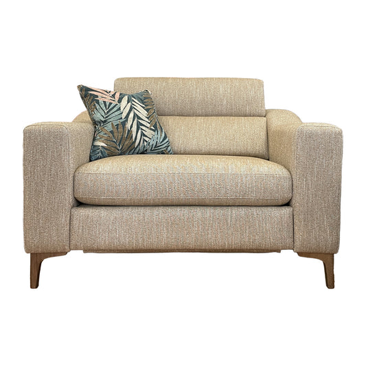 A beige upholstered snuggler chair with a decorative cushion on top, placed against a white background.