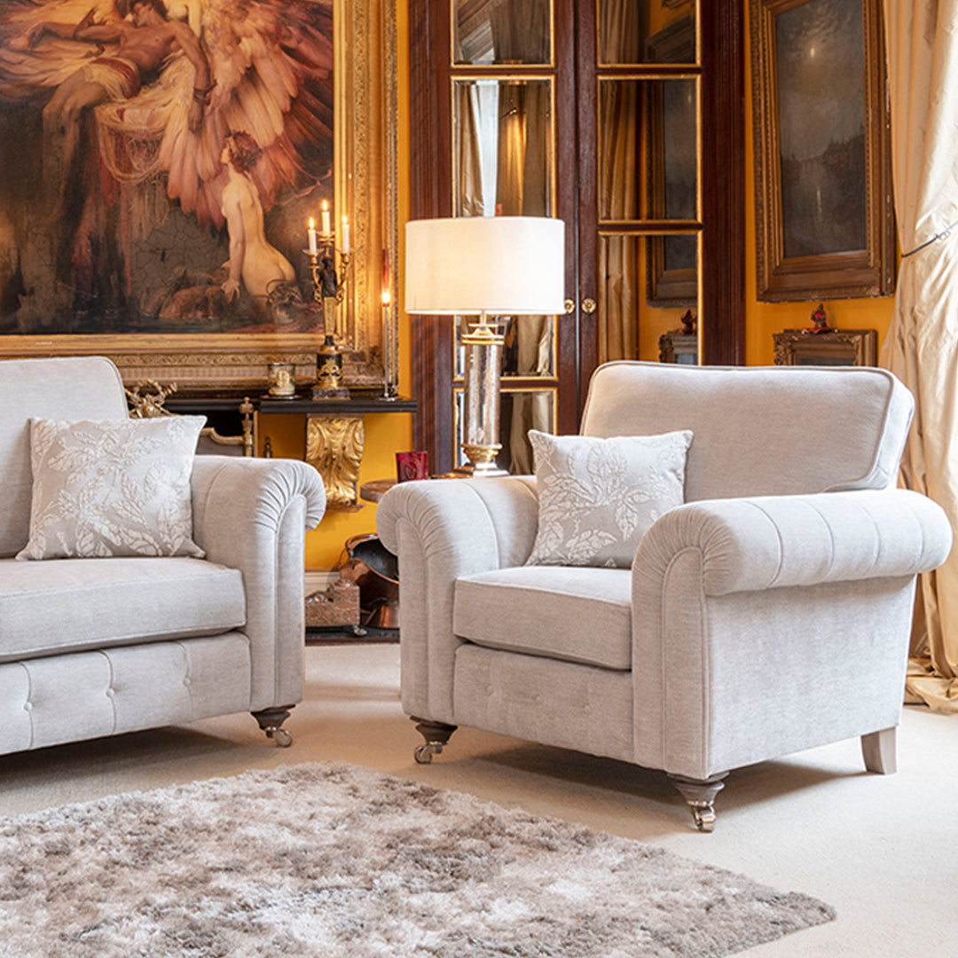 An image of a cream armchair in a grand room with an oversized painting.