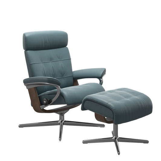A modern recliner chair with a plush top cushion and an adjustable headrest, paired with a matching footstool, upholstered in a blue leather material.