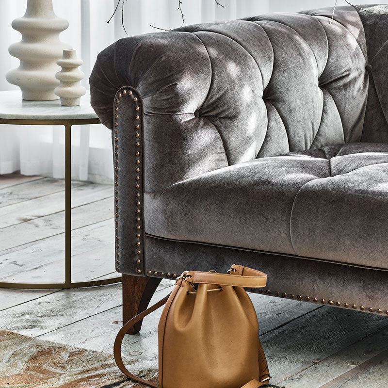 A lifestyle image of the Luisa Shallow Sofa. The sofa is placed on a wooden grey floor and the sofa is in  a Grey fabric. 